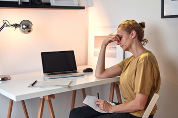 Woman working from home on a laptop and having headache.