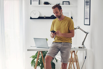 Man using smartphone at home while making pause from work.