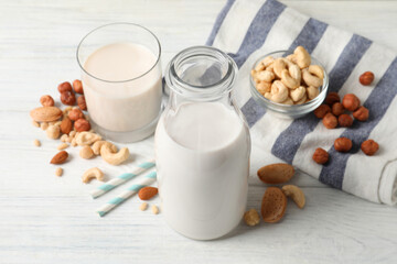 Different nut milks on white wooden table