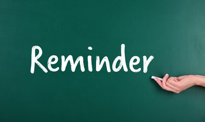 Woman writing word Reminder on chalkboard, closeup