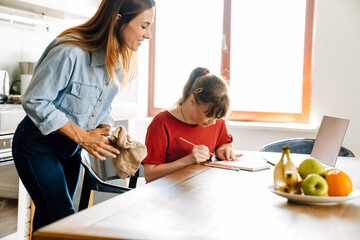 White woman helping her daughter with down syndrome doing homework