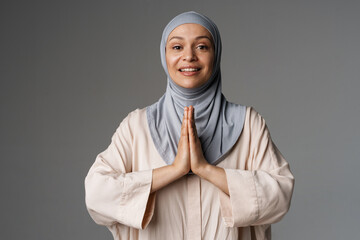 Middle eastern woman in hijab gesturing and smiling at camera