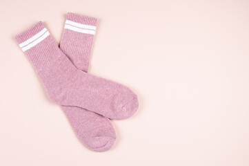 Pair of pink socks with white strips on pastel pink background with copy space