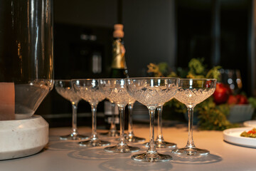 Raw of crystal wine glasses with bottles of champagne in the background. Luxury table setting. Selective focus