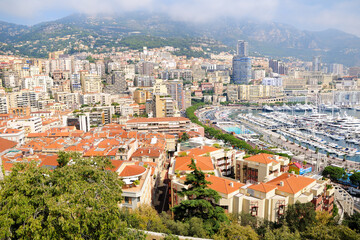 Panoramic view of Monte Carlo harbor in Monaco. Port Hercules. Yachts in the port. Aerial view, cityscape. Roofs of houses in the foreground.
