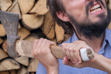 A man is fragmentary in his hands with an axe on the background of a woodcutter