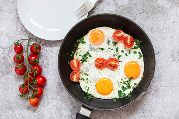 Fried eggs in a frying pan. On a concrete gray background. On the plate