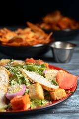 Caesar Salad made of chicken meat, tomatoes, eggs, fresh arugula, croutons, cheese and sauce on top.