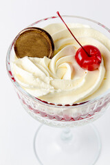 Traditional Italian dessert - Tiramisu dessert with cherry. Served in a tall glass over white background.