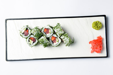 Sushi rolls with tuna, cucumber and cream-cheese in chopped dill. Served on a white plate over white background.
