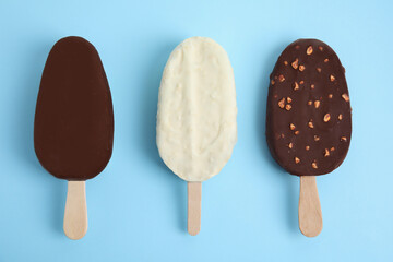 Glazed ice cream bars on light blue background, flat lay