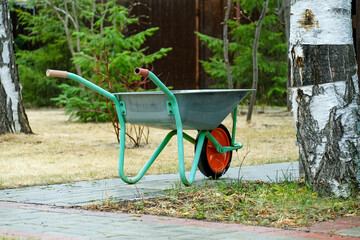 A garden wheelbarrow stands on the path. Transport trolley