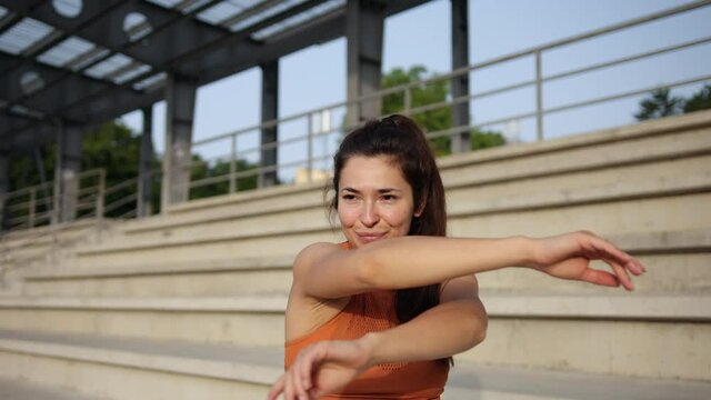 young, attractive woman does some shoulder stretches prior to outdoor workout.