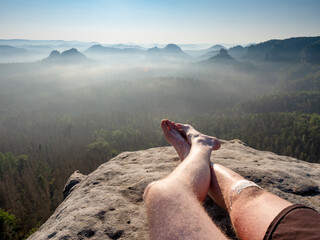 Resting man. Traveler\'s naked legs pointed towards to mountain peak