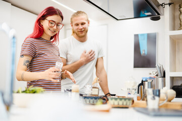 Young white couple smiling while cooking together in kitchen