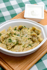 Italian ravioli with spinach and cheese close-up, rustic style. Served in a white pan over rustic wooden board
