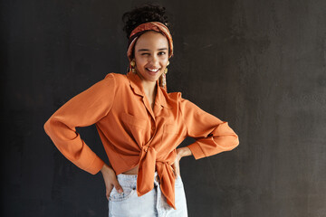 Young hispanic woman in earrings smiling and winking at camera