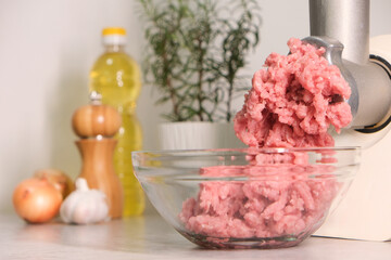 Minced meat grinder on the kitchen table in a transparent bowl.