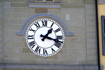 Black and white clock at the clock tower of the old town of Nyon on a sunny summer day. Photo taken August 11th, 2021, Nyon, Switzerland.