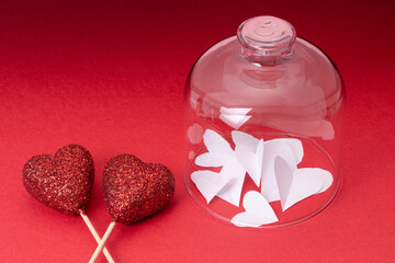 Closeup of paper hearts under glass with heart sticks on the red background.