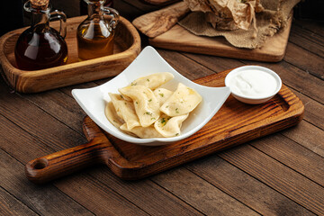 Russian vareniki dumplings with sour cream on wooden background