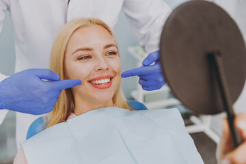 Young fun happy satisfied caucasian blonde woman 20s with toothy smile looking at mirror...