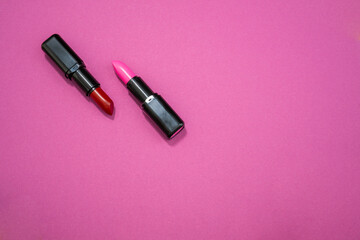 Fashion cosmetics photo of red and pink lipsticks on a pink background 