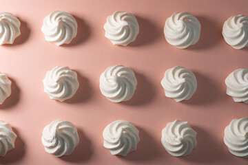 Closeup of french mini meringues cookies on pink as food background.