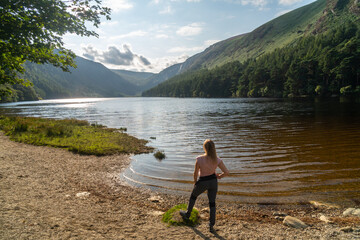 Girl standing at the lake shore at the Glendalough Valley. Panoramic idyllic view. County Wicklow Upper lake from miners way, Glenealo valley, Wicklow way, County Wicklow, Ireland.