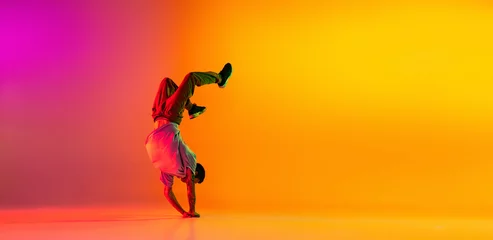 Fotobehang Flyer with young stylish man, break dancing dancer training in casual clothes isolated over gradient pink yellow background at dance hall in neon light. © master1305