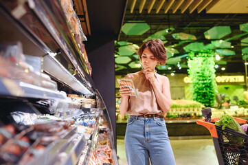 Young minded woman in casual clothes shopping at supermaket greengrocery store buy choose meat...