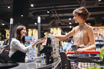 Young smiling woman wear casual clothes mask shopping at supermaket stand at store checkout giving...