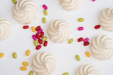 Closeup of french mini meringues cookies on light white background with colourful candys 