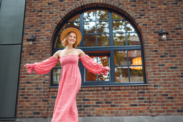 Young smiling happy fun woman 20s wear pink dress hat going walk with outstretched hands dance in...