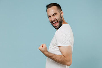 Side view young happy man in blank print design white t-shirt do winner gesture clench fist...