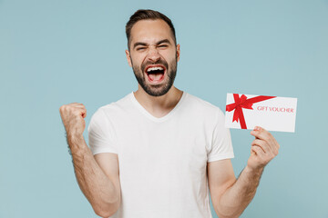 Young happy overjoyed man in blank print design white t-shirt hold gift certificate coupon voucher...