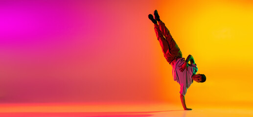 Flyer with young stylish man, break dancing dancer training in casual clothes isolated over gradient pink yellow background at dance hall in neon light.