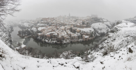  Panoramic view of city landscape of snowy old city with clouds and snow; Cathedral and Alcazar of Toledo during the storm Filomena, World Heritage Site, Spain. Horizontal view