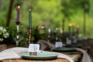 Close up of rustic place settings and candles for a woodland naming ceremony.