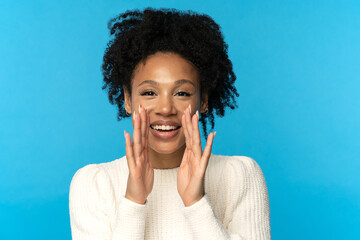 Young happy african woman shouting holding hands at open mouth. Excited cheerful black female...