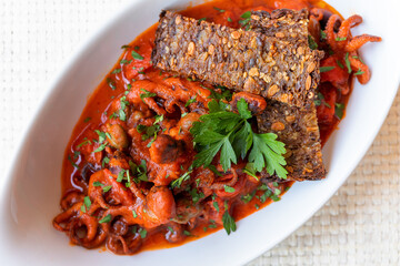 octopus; cherry tomatoes; olives; capers; tomato sauce; ready to eat; tasty; italian cuisine; recipe; traditional; gourmet; restaurant; dish; food; fish food; bruschetta; crusty bread; gravy; cooked