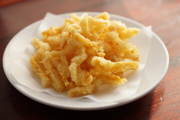 Angle view of Deep fried fish maw with a white dish on wood table.