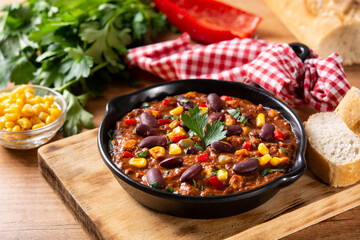 Traditional mexican tex mex chili con carne in iron pan on wooden table