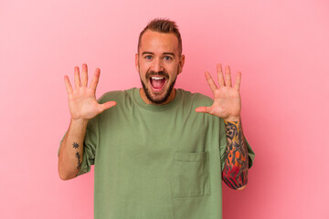 Young caucasian man with tattoos isolated on pink background  receiving a pleasant surprise, excited and raising hands.