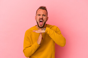 Young caucasian man with tattoos isolated on pink background  showing a timeout gesture.