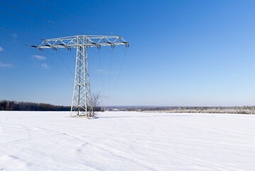 Electric power tower pole or pylon in winter snow covered landscape background
