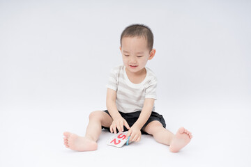 A little asian boy takes a portrait in a white background shed