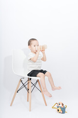 A little asian boy takes a portrait in a white background shed