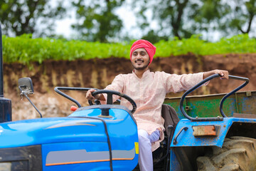 Technology and people concept, Portrait of young indian farmer with tractor