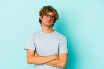 Young caucasian man with make up isolated on blue background  tired of a repetitive task.